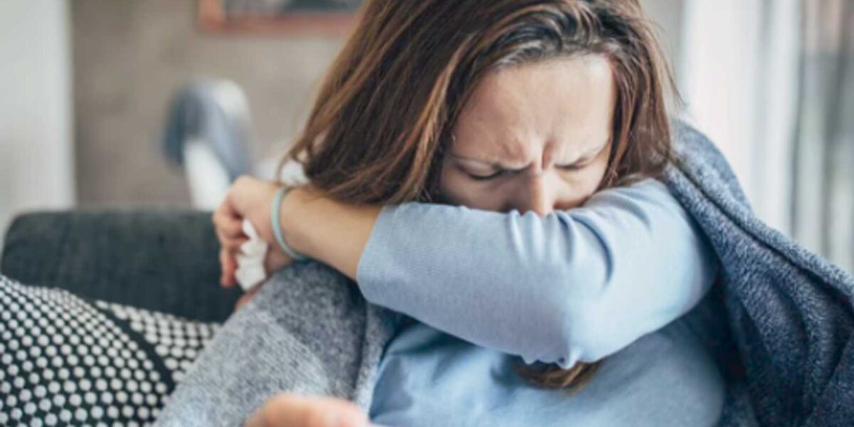 Donna con febbre sul divano, avvolta nella coperta, ha preso l'influenza
